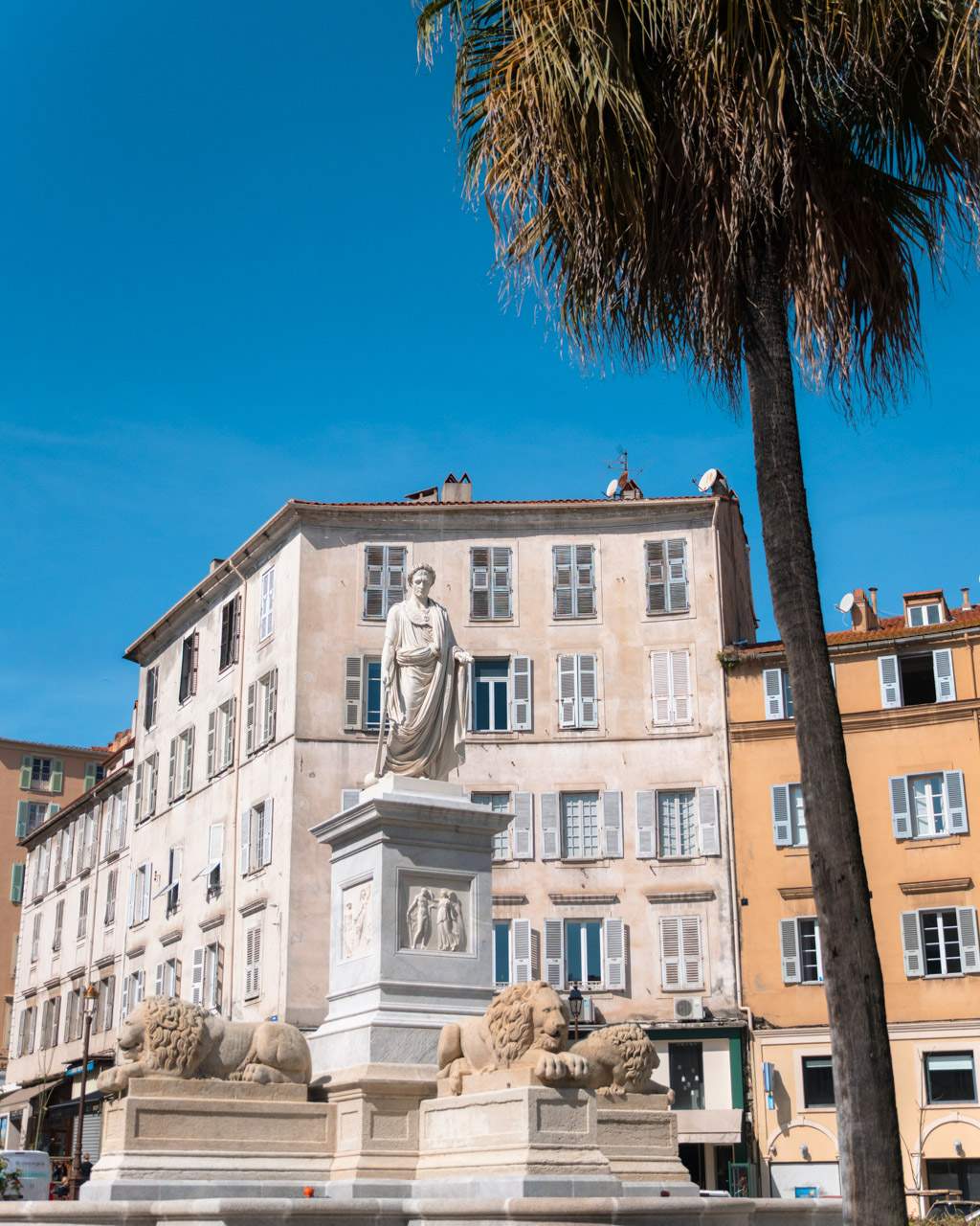 A statue of Napoleon dressed as a Roman emperor above a fountain with lions in Ajaccio