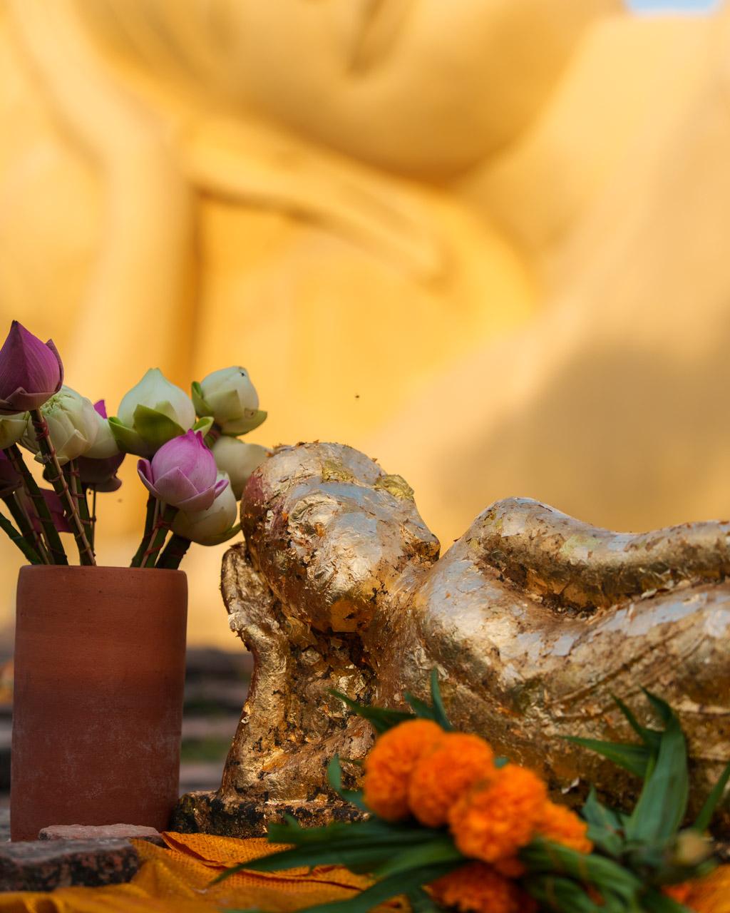 A small golden reclining golden Buddhha in front of the big reclining Buddha at The reclining Buddha at Wat Lokayasutharam
