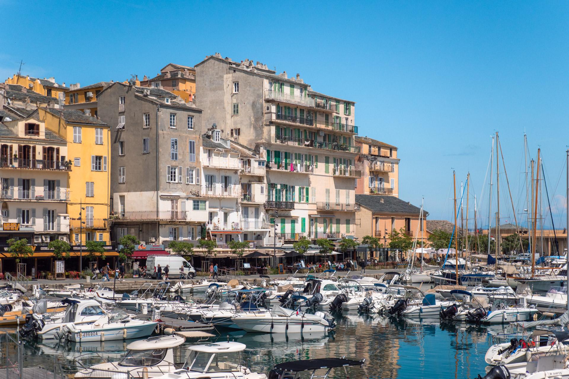 Bastia's old harbour with pastel-coloured houses, outdoor cafés and small boats.