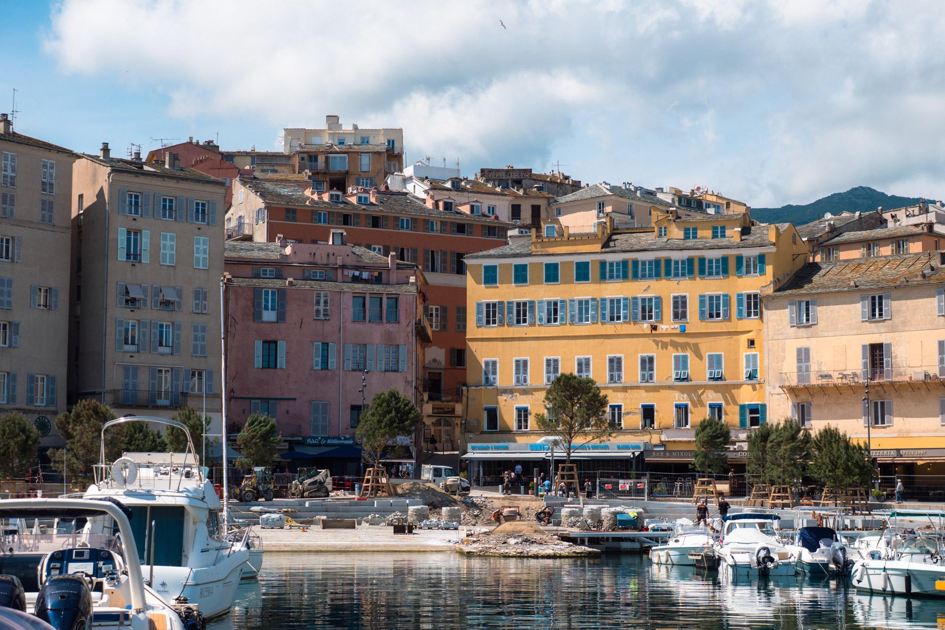 The harbour under renovation in Bastia with boats moored in front.