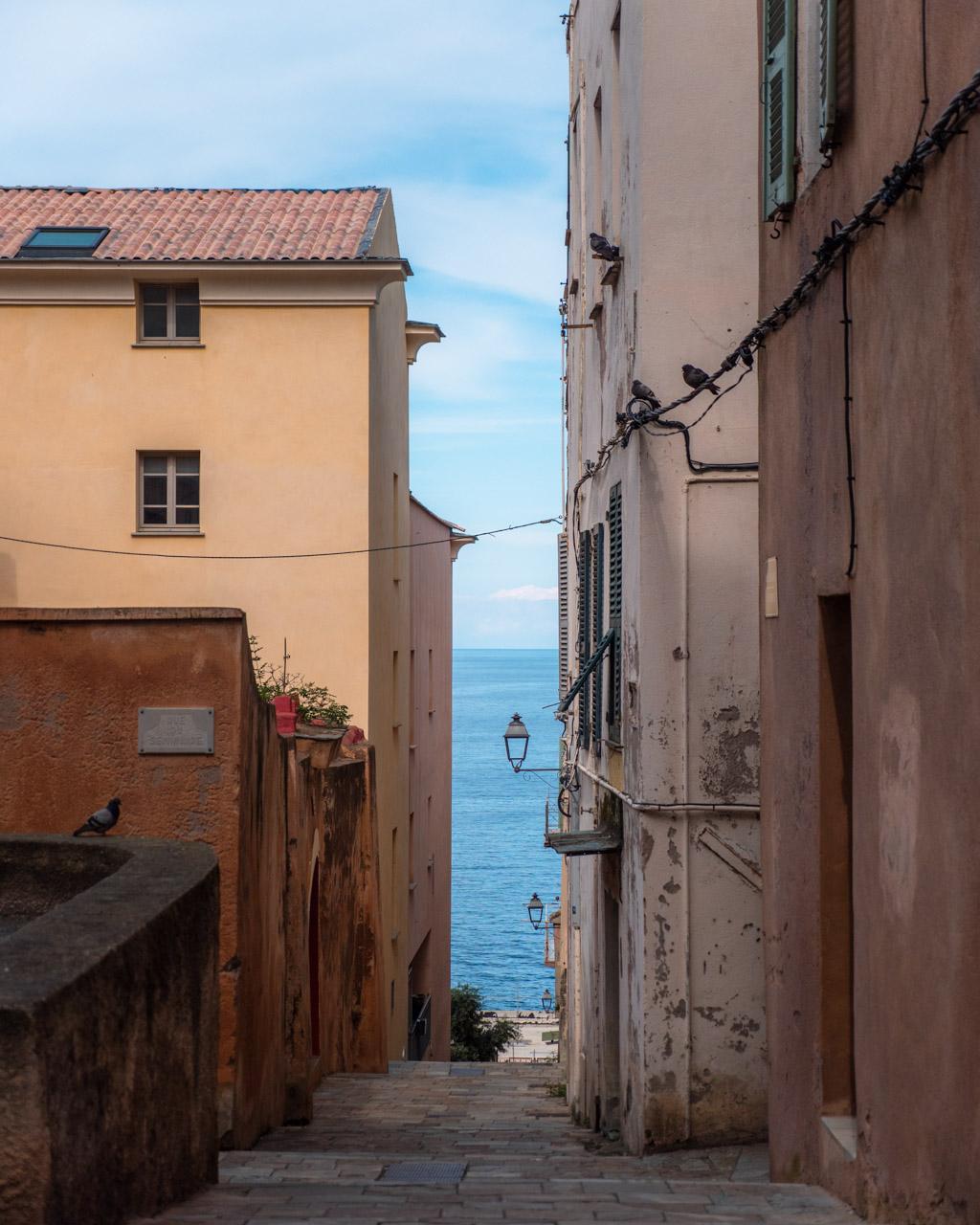 Narrow cobbled street in Bastia's citadel lined with colourful old houses.