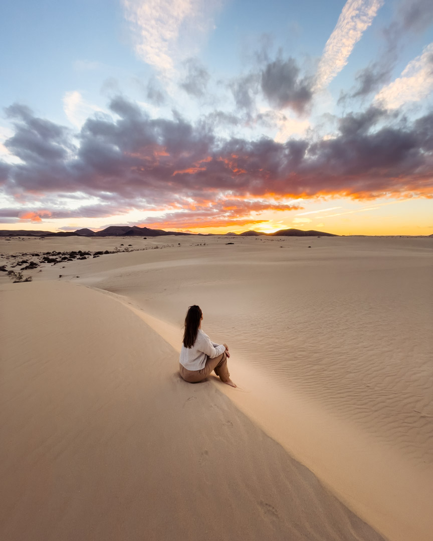 Victoria sitting at a dune in Corralejo Sand Dunes in Fuerteventura at sunset