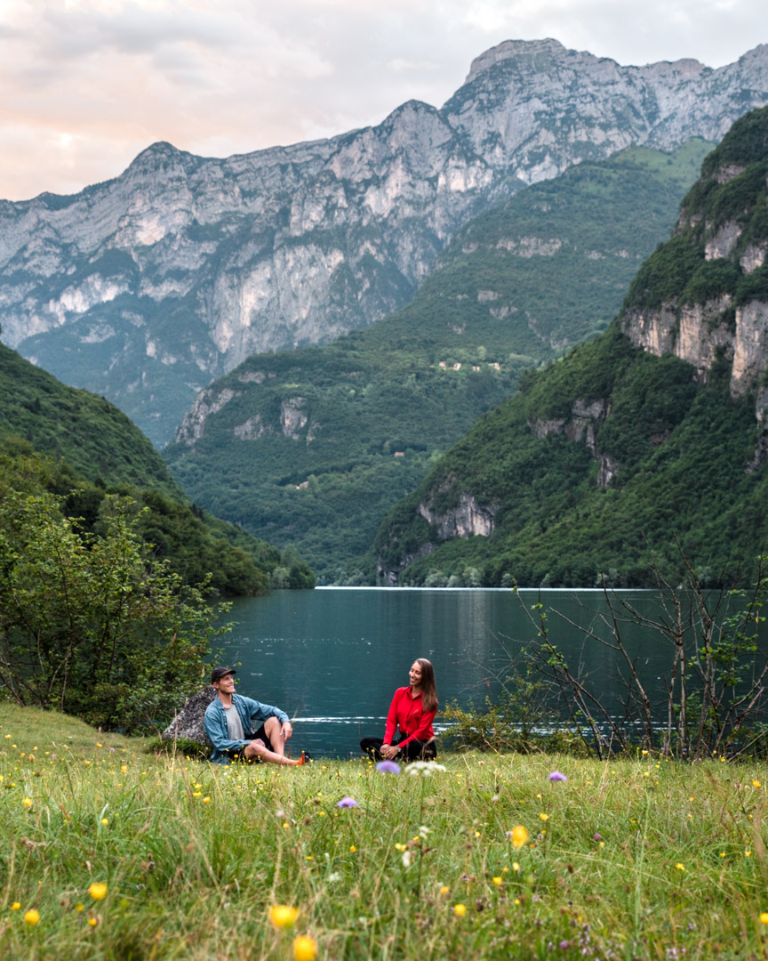 Digital nomad couple Alex & Victoria sitting by the lake in Italy