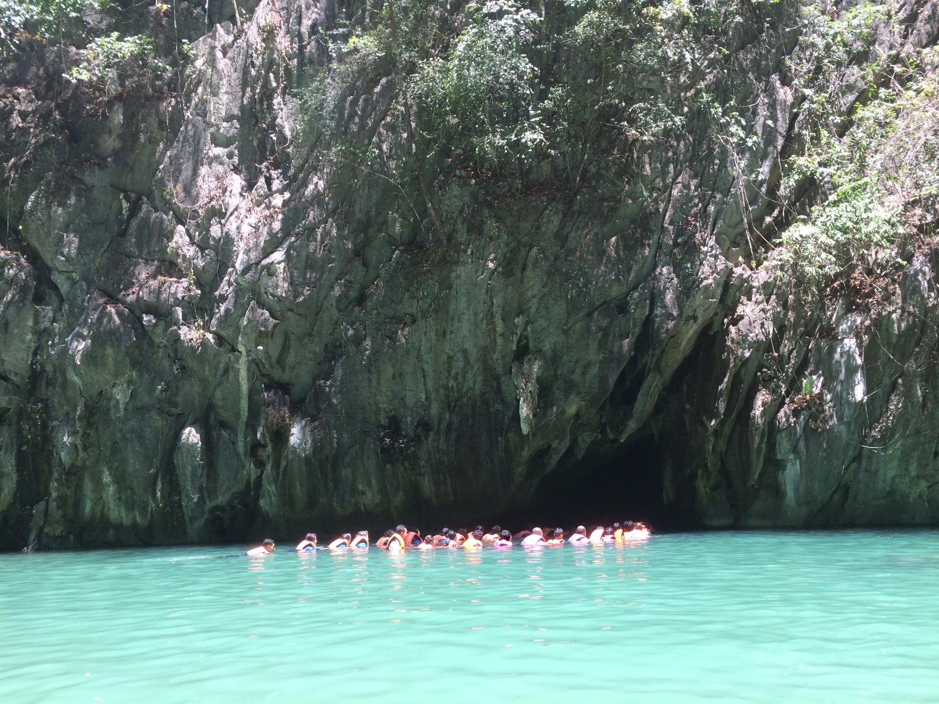 Emerald Cave entrance from the outside with a long line of people wearing orange life jackets