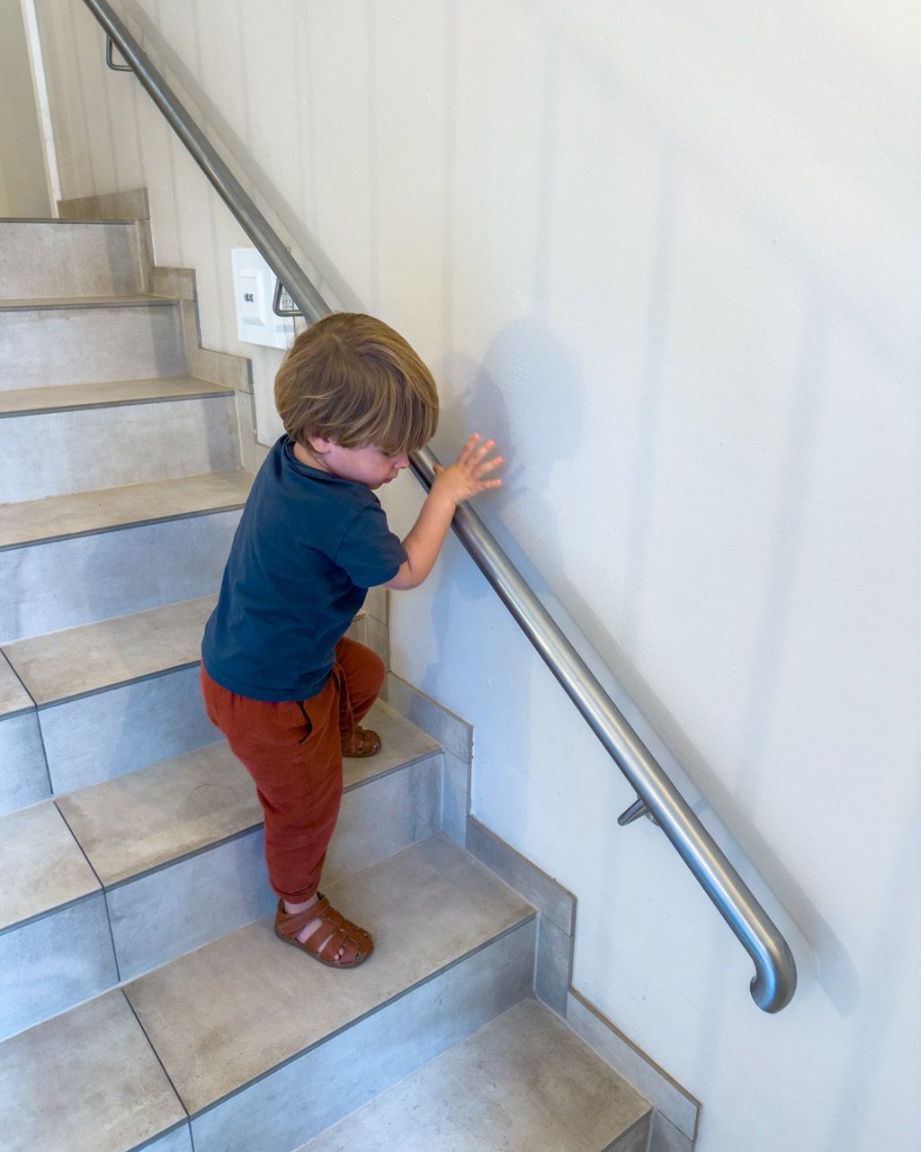 Adrian using the lower, child-height handrail on the main stairs at Leiners