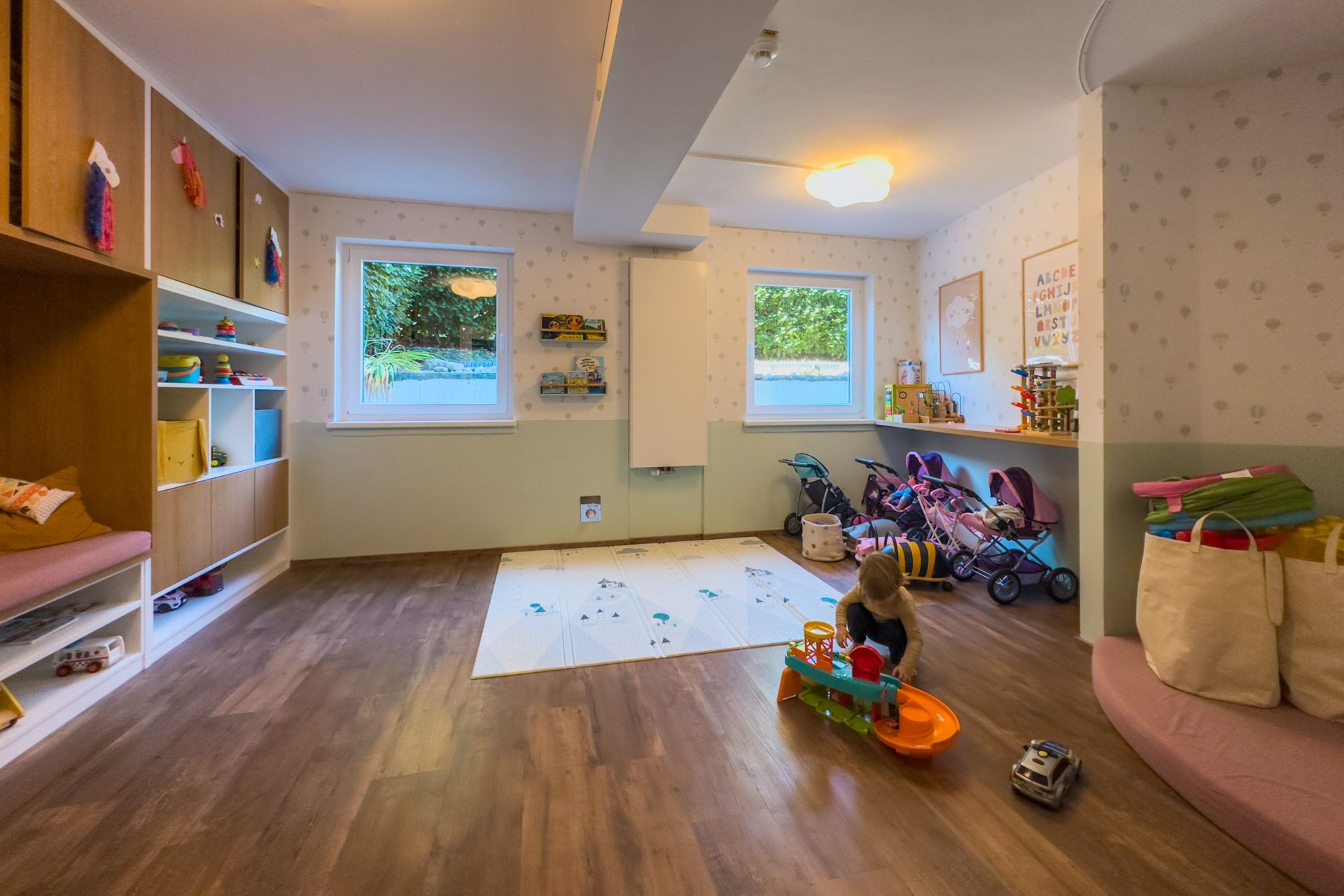 Toddler room in the childcare centre at Leiners with doll prams and a play mat