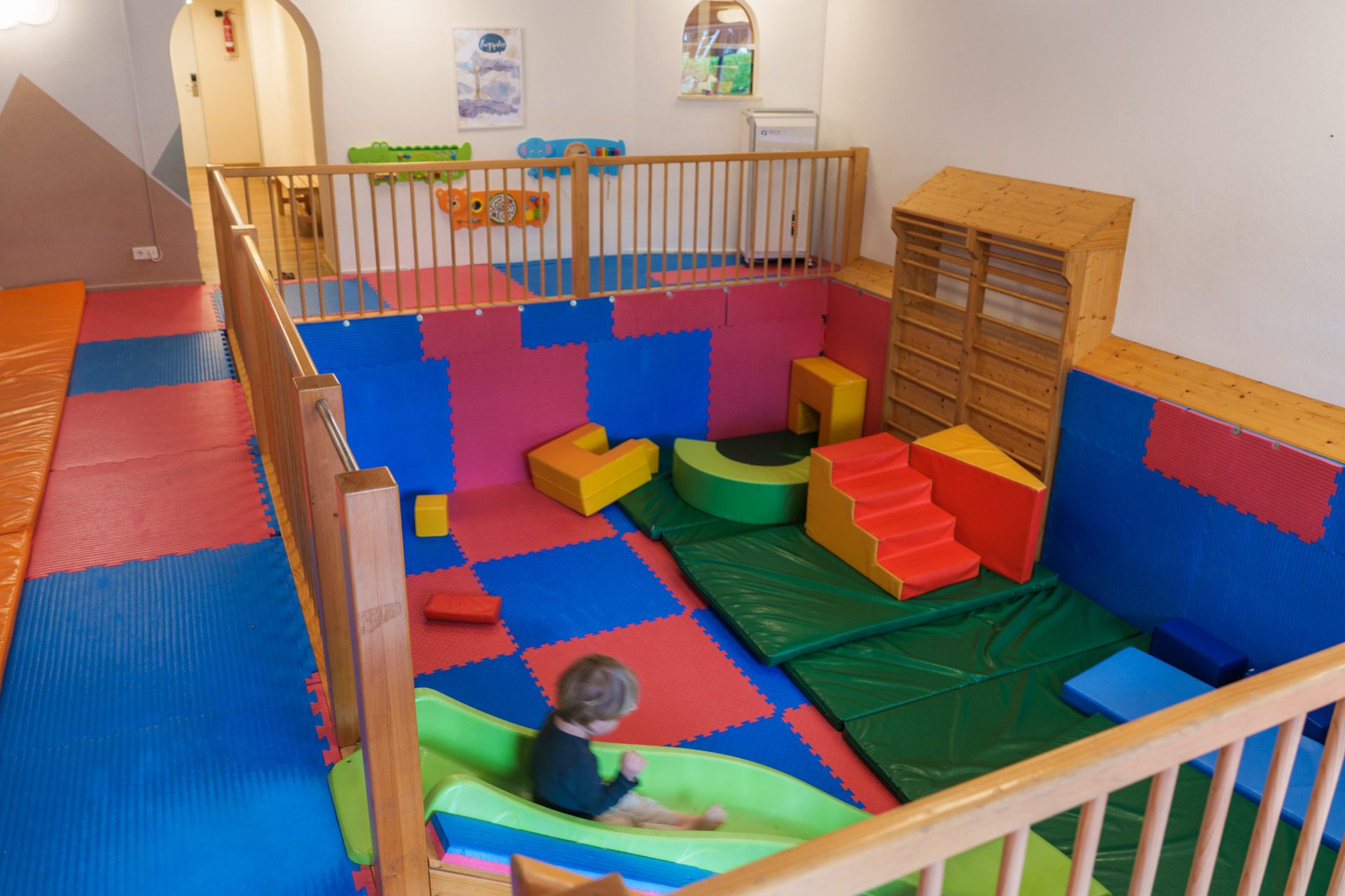 Child going down the green slide in the soft-play room