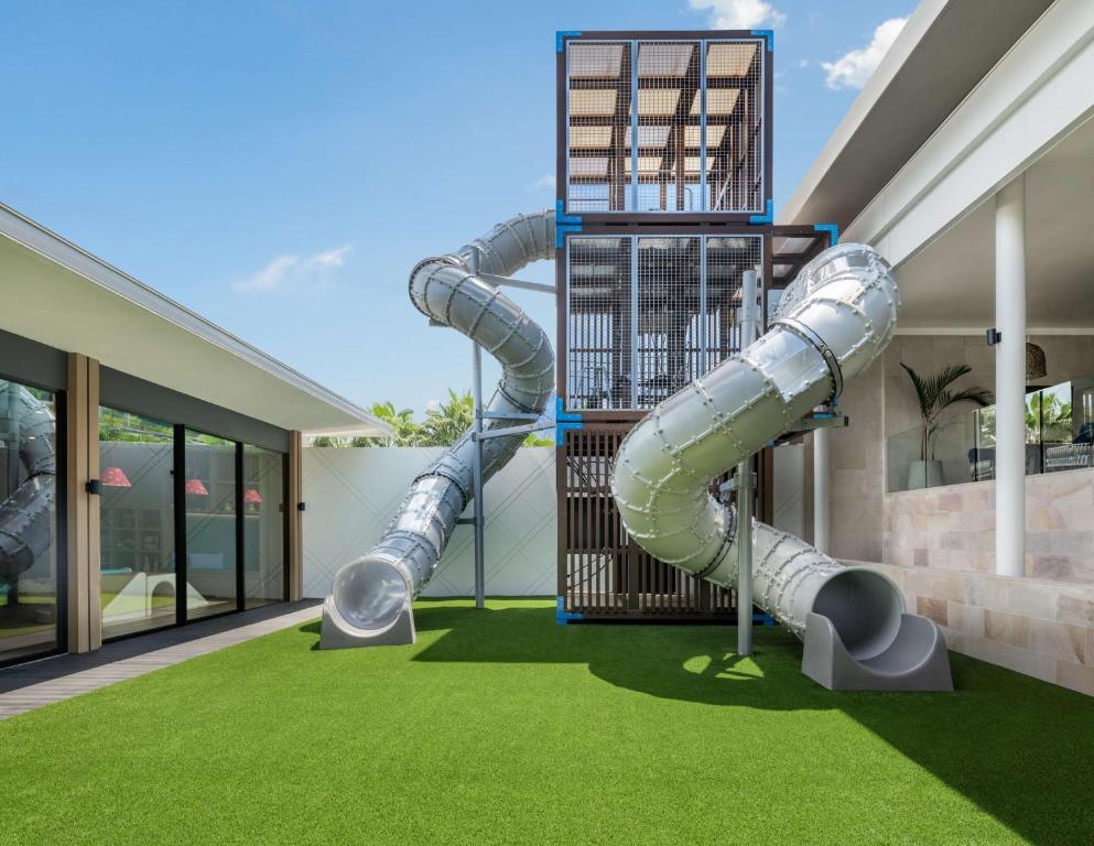 Hyatt Regency Phuket kids club exterior with two twisting metal slides and climbing tower on artificial grass.
