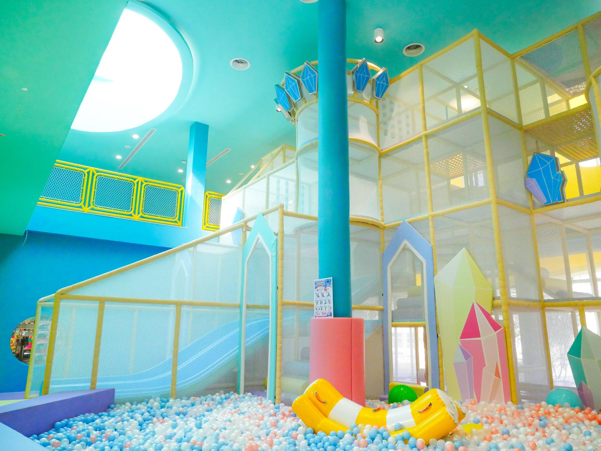 Colorful kids' club interior with turquoise ceiling, yellow-framed play structures, ball pit, and geometric decorative elements at Katathani Phuket resort.