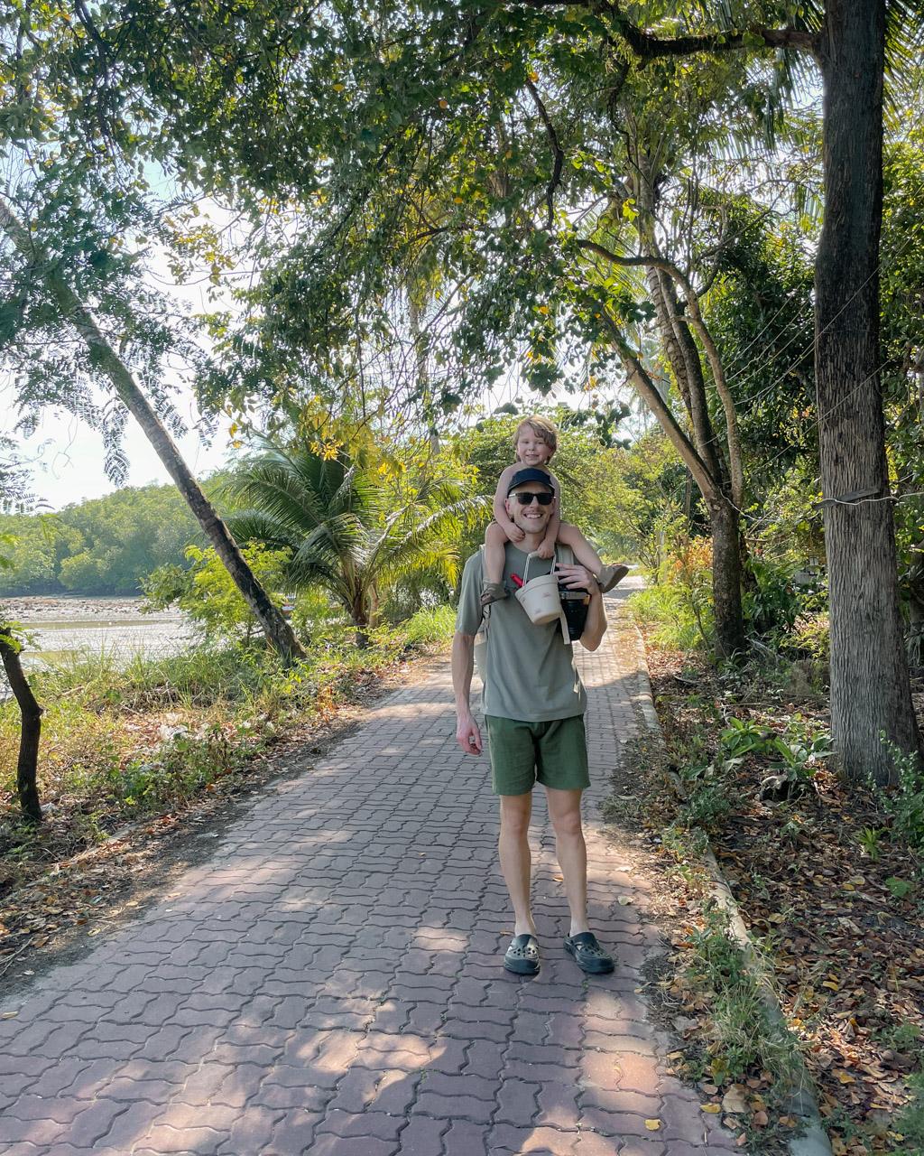 Alex walking down one of the lanes on Koh Mook with Adrian on his shoulders.
