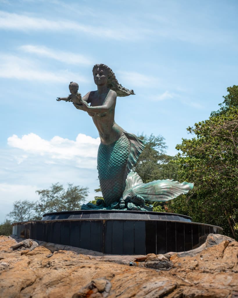 The mermaid with the child stands at the end of Sai Kaew Beach