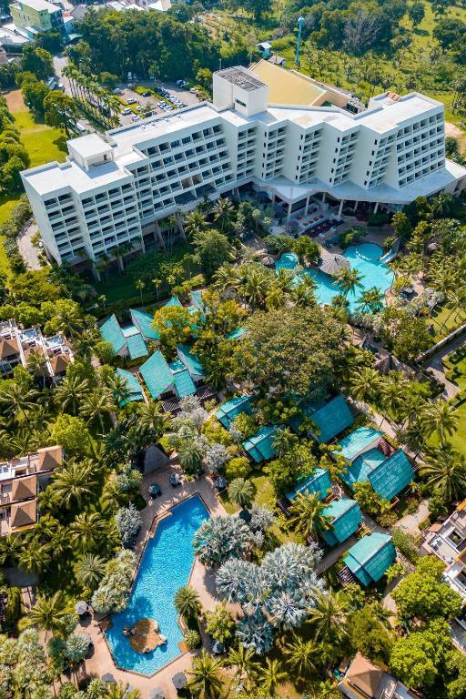 Aerial view of Paradox Karon Phuket resort with white modern buildings, multiple turquoise swimming pools, and surrounding tropical palm trees.