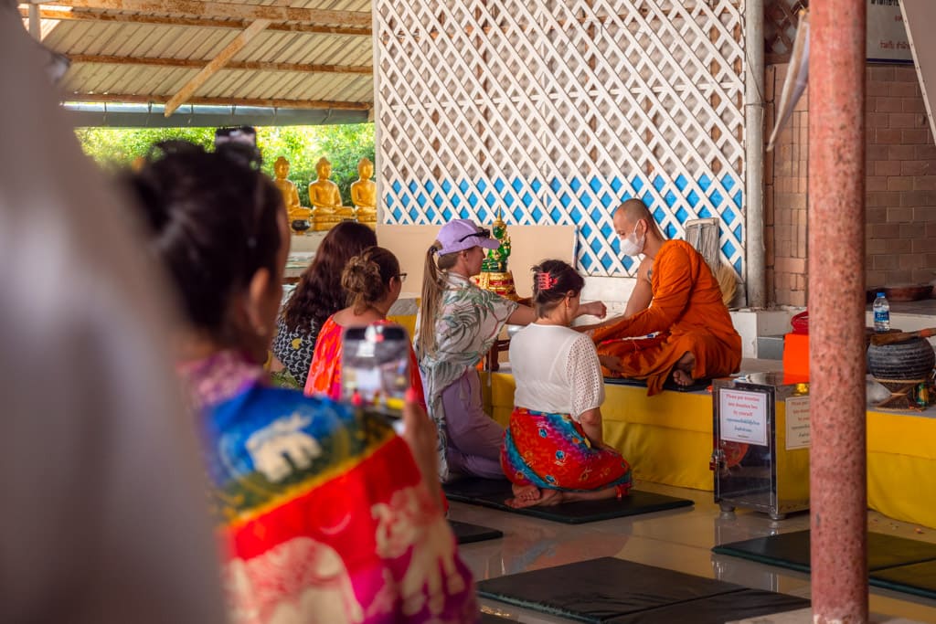 Tourists being blessed by a monk for a donation to the temple
