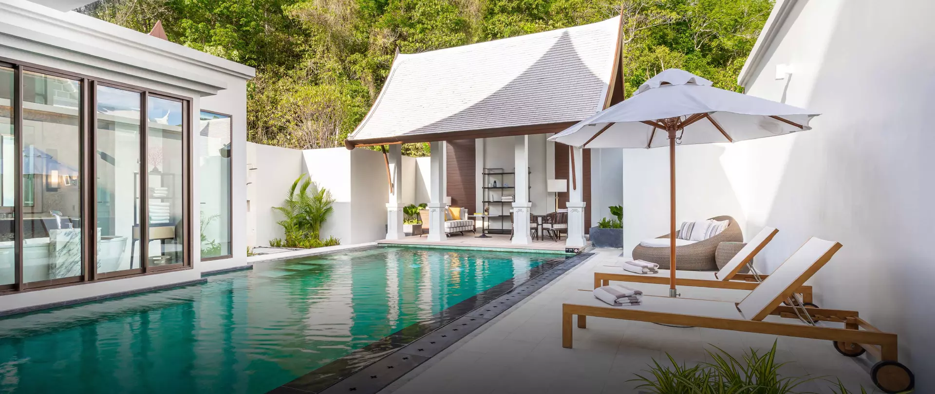 Phuket Intercontinental 2-bedroom villa with turquoise pool, white lounge chairs, umbrella, and modern architecture surrounded by lush greenery.
