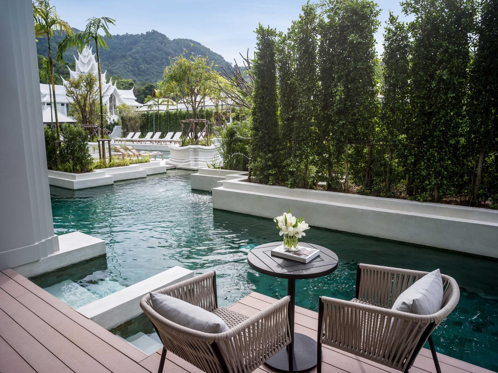 Pool access room at Phuket InterContinental with turquoise water, lounge chairs, white flowers, and mountain views.