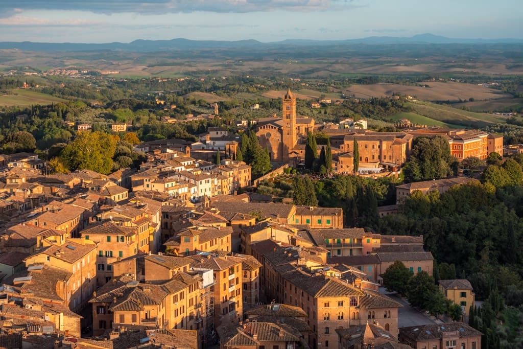 Houses in Siena with the Tuscan landscape with hills in the background - seen from Torre del Mangia