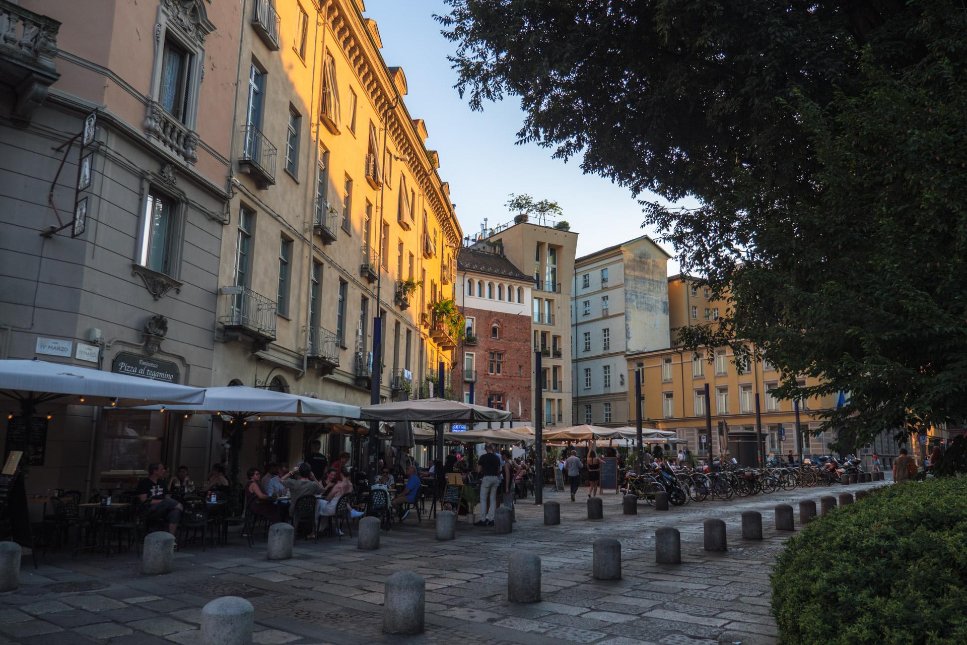 Square with people eating at cafés and restaurants in Turin at dusk